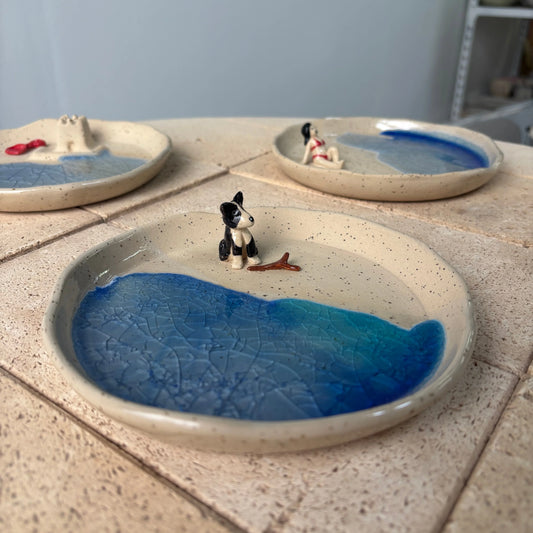 Platos de cerámica artesanal decorativo de Hecho por Su, pintado a mano, personalizado, con figura de perro en la playa, esmalte azul brillante. Palabras clave: cerámica artesanal, pintada a mano, personalizada.